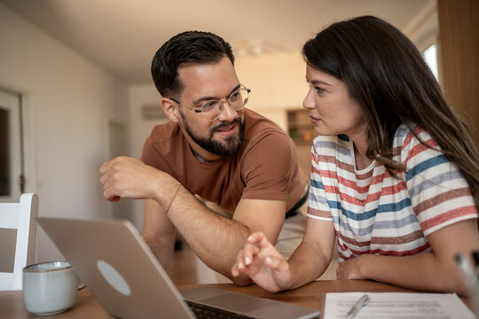 Couple using laptop and discussing home finances at table