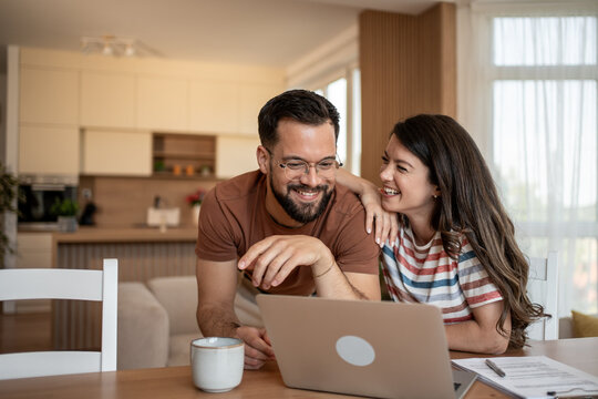 Happy couple watching funny videos on laptop at home