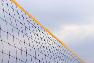 Beach volleyball net close-up. Fragment of a volleyball net on the beach against a cloudy sky....