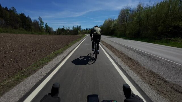 Cyclist riding on a newly constructed bicycle path in rural Germany. The fresh, paved bike lane ensures safe, eco-friendly transport between towns and blends with the natural forest landscape