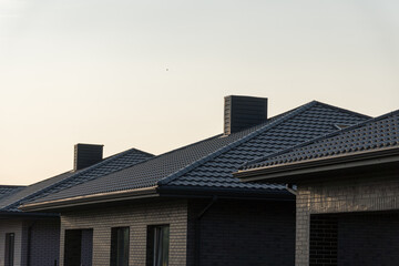 Several modern brick houses showcase their tiled roofs as the sun sets, creating a tranquil atmosphere in the neighborhood