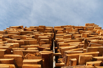 Wooden logs are neatly stacked in a lumber yard, showcasing the texture and depth of the wood...