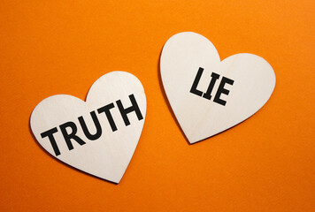 Truth or Lie symbol. Concept word Truth or Lie on wooden hearts. Beautiful orange background....