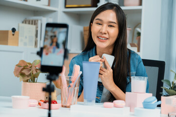 Young beautiful Asian reviewing cosmetic makeup and skin care collection, talking customer on...