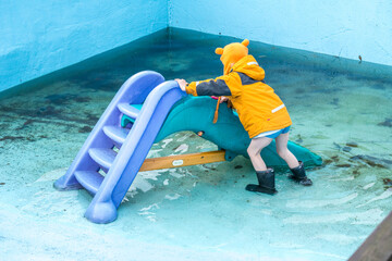 Child climbing colorful slide in flooded pool.