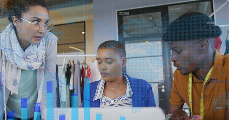 Analyzing data charts on laptop, design team working in design studio, with measuring tape