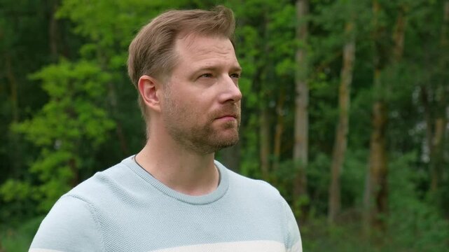 Handsome young man standing outdoors. Male thinking looking around feel happy, calm and serious. Green park background. Guy business employer, businessman manager inspired in nature. Diversity People