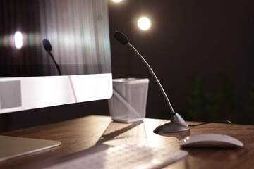 Microphone and computer on wooden desk indoors