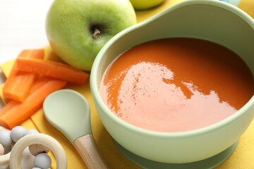 Baby food. Tasty puree in bowl, different ingredients and teether on table, closeup