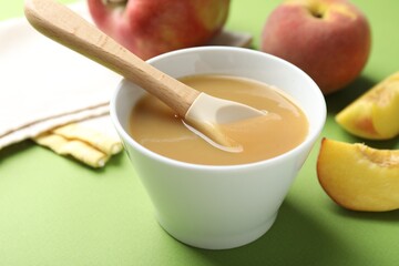 Baby food. Tasty puree in bowl and ingredients on green background, closeup