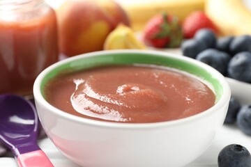 Baby food. Tasty puree in bowl, spoon and ingredients on white table, closeup