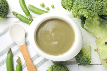 Baby food. Tasty puree in bowl, spoon and ingredients on white wooden table, flat lay