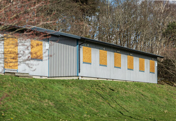 Naklejka premium Boarded metal building with wooden window covers.