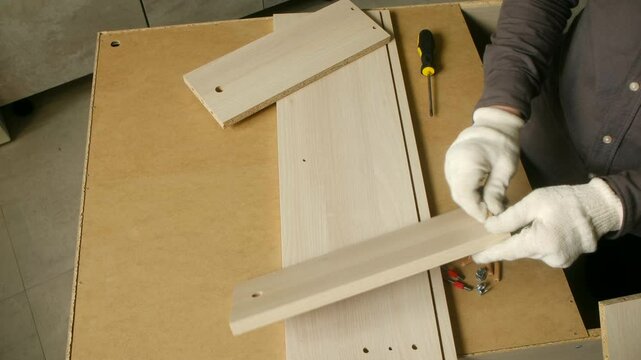 Furniture assembly process involves joining wooden planks with dowels and screws, showcasing craftsmanship and precision in creating functional furniture pieces
