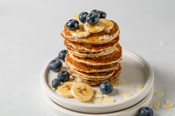 Stack of American banana pancakes with fresh blueberries, honey and almond petals. Healthy eating. Morning tasty homemade breakfast. Top view, selective focus.