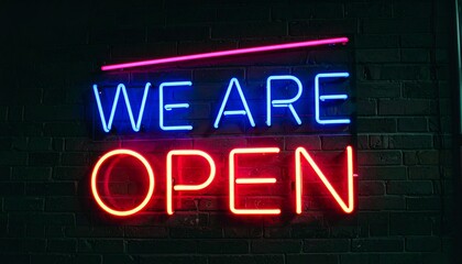 Neon sign saying "We Are Open" on a brick wall at night. The sign is brightly lit in red and blue neon.
