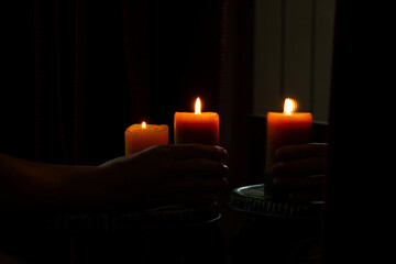 Female hand holding candle near mirror in dark room