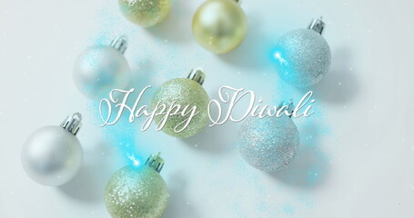 Displaying glittery spherical ornaments and Happy Diwali text overlay in studio, with glitter dust