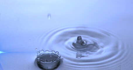 Capturing droplet hitting water in studio, forming crown-shaped and column splashes with ripples