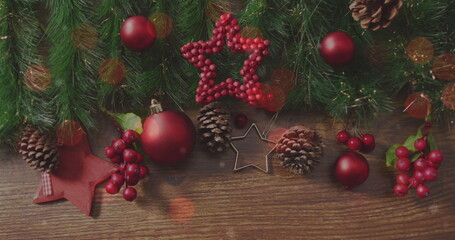 Displaying Christmas decor on wood table with red baubles, pine branches and star cookie cutter