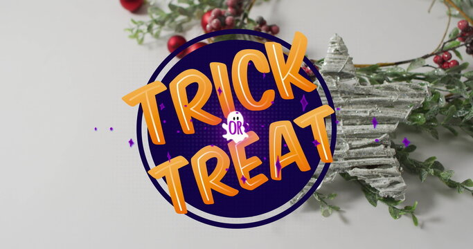 Fototapeta Displaying purple Trick or Treat sign on white tabletop, with wreath, berries and star ornament