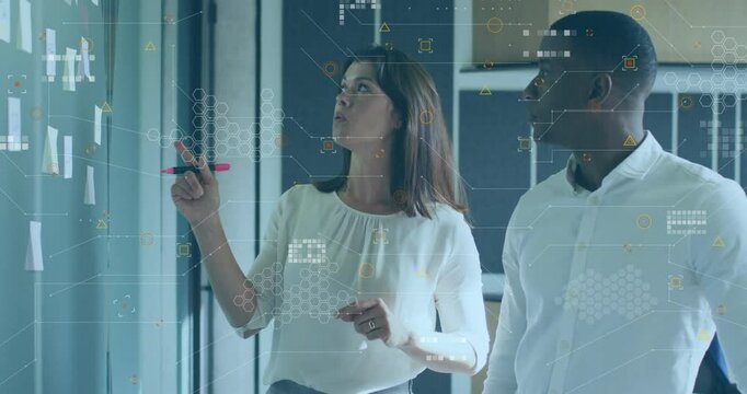 Woman scanning board then picking marker and grouping notes while man nodding in business planning