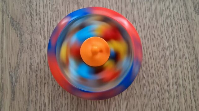 Colorful spinning top in motion on wooden surface with blurred swirl pattern