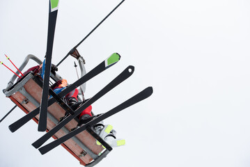 Skier ascending on chairlift with ski equipment on cloudy winter day
