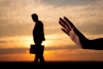 Business hand gesture stops man walking away during sunset