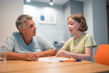 A portrait of grandmother and granddaughter doing homework together at home.