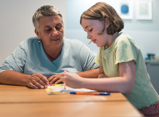 A portrait of grandmother and granddaughter doing homework together at home.	
