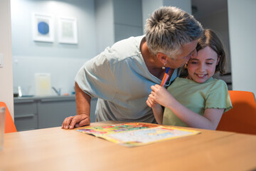 A portrait of grandmother and granddaughter doing homework together at home.	
