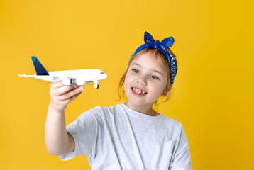 Little caucasian child girl playing with aircraft,airplane on yellow background.Journey flight...