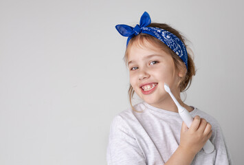 Caucasian child girl's portrait holding electric toothbrush.Female kid smiling face with tooth...