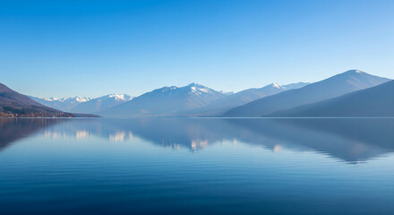 Fototapeta premium Calm lake view with mountain reflection and soft blue sky