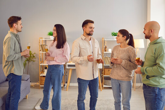 Diverse company of friends, coworkers or colleagues communication during event or party celebration. Holding glasses of wine or champagne, happy people and enjoyable gathering.