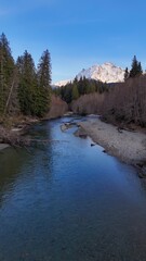 A scenic view of a river flowing towards a snow capped mountain under a clear blue sky in daytime