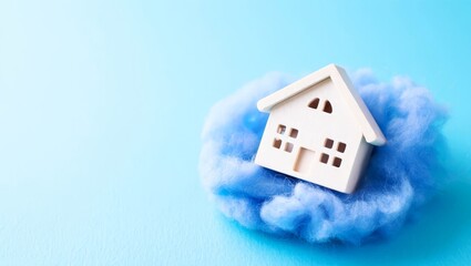 A miniature house surrounded by a soft, fluffy, light blue blanket, symbolizing warmth.