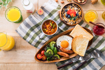 【朝食イメージ】トーストと目玉焼き。ウィンナーとサラダ。ミネストローネとミューズリー。オレンジジュースと牛乳。