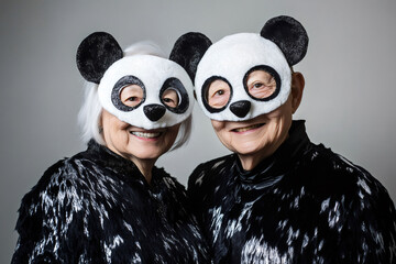 Two joyful seniors dressed in playful panda costumes, sharing smiles and laughter, radiating happiness at a festive costume party