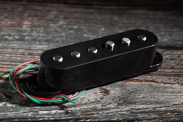 black single coil pickup on black wood background