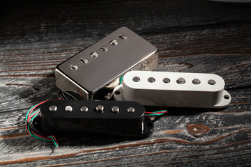 various guitar pickups on black wood background