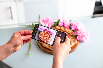 happy pastry chef woman taking photo of fruit pie on cellphone at cozy kitchen