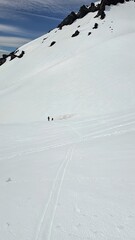 Two people standing on a vast snow covered landscape with mountain and sky in the background view