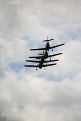 Low angle view of four vintage propeller planes flying in close formation against a dramatic cloudy...