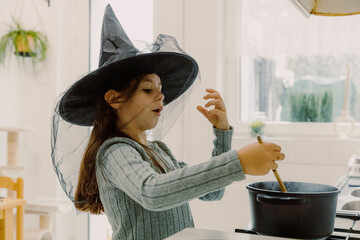 Cute girl in a witch hat cooks terrifying Halloween pasta