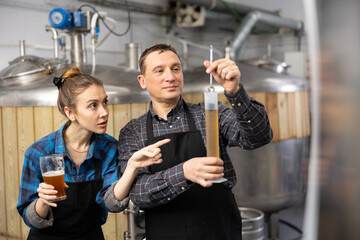 Fototapeta premium Woman and a man check the amount of alcohol in beer at a private brewery