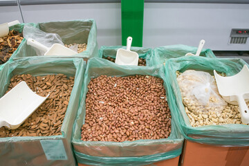 Bulk nuts and seeds displayed in bins at a market during daytime, showcasing a variety of healthy snacks in an organized setting