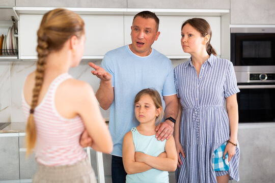 Family scene in kitchen, unpleasant conversation Parents stand face to face with daughter and scold for disobedience, unreasonable behavior