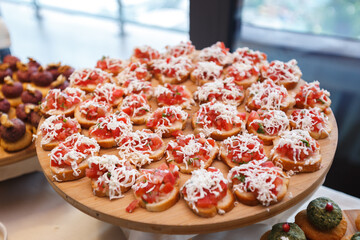 Sandwiches with tomatoes and cheese on a wooden tray